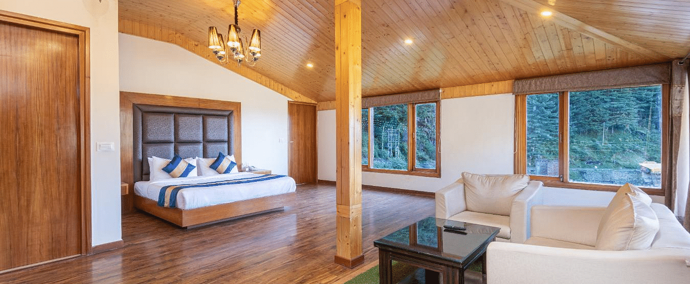 A spacious and luxurious hotel room with a king size bed, a sitting area, and large windows offering scenic views  | DLS Serenity Resort and Spa